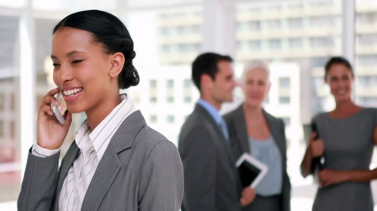 Businesswoman having a phone call with colleague in background