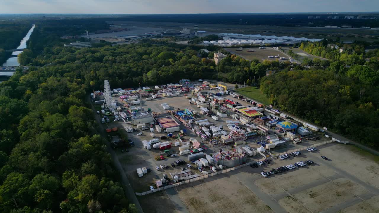 outdoor forest fairground, funfair, carnival with rides and stalls surrounded by forest. Lovely aerial view flight overflight flyover drone