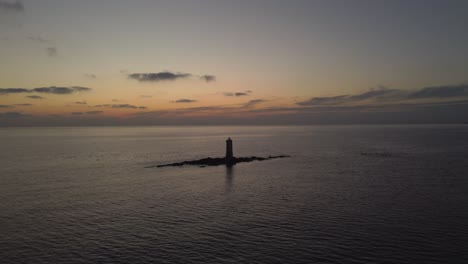 solitary offshore lighthouse in calasetta, aerial approach at dusk sunset