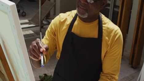 african american senior man standing on a terrace and painting