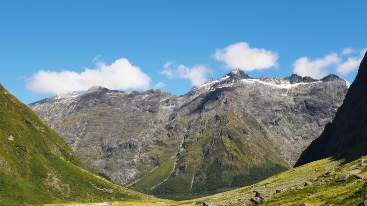 zoom en la toma de la hermosa cordillera contra el cielo azul y la luz del sol en nueva zelanda - vegetación de hierba y plantas en la cima de la montaña