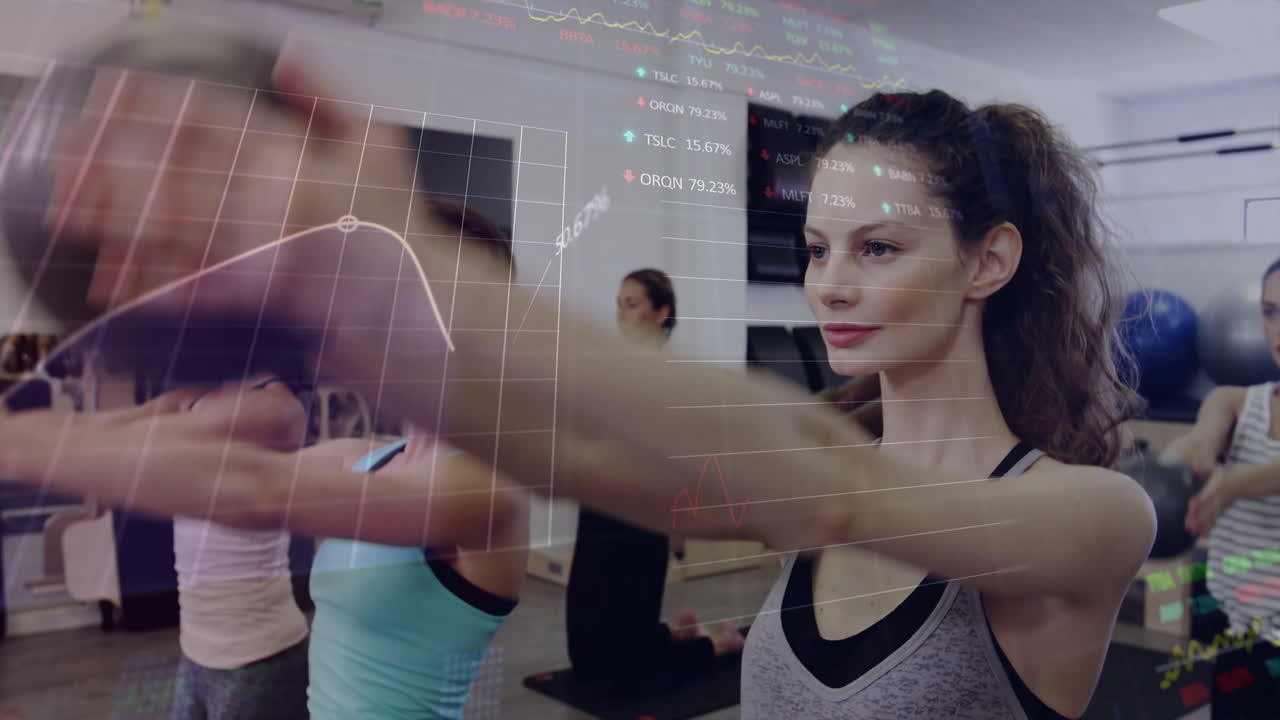 Group lifting medicine balls in fitness gym, displaying stock charts and data overlays