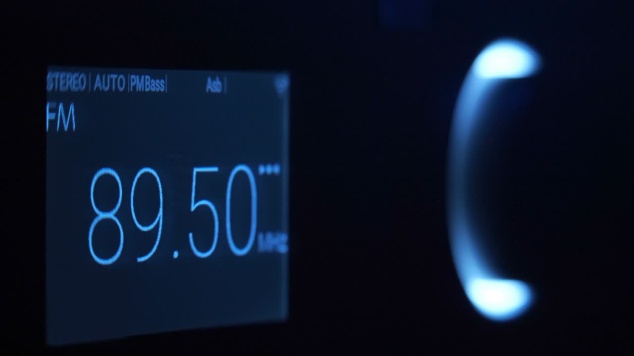 en la oscuridad, la mano gira el control de volumen, iluminado por luz azul