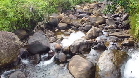 drone-shot,-flying-over-flowing-water-on-rocks