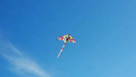 a vibrant kite soaring against a clear, blue sky capturing the joy and freedom of outdoor activities under bright sunshine