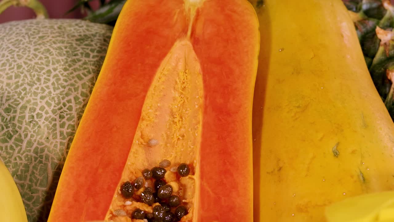 A vibrant arrangement of sliced papaya, diced mango, and whole pineapple, showcasing tropical freshness.