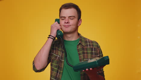 Cheerful-tourist-man-secretary-talking-on-wired-vintage-telephone-of-80s,-says-hey-you-call-me-back