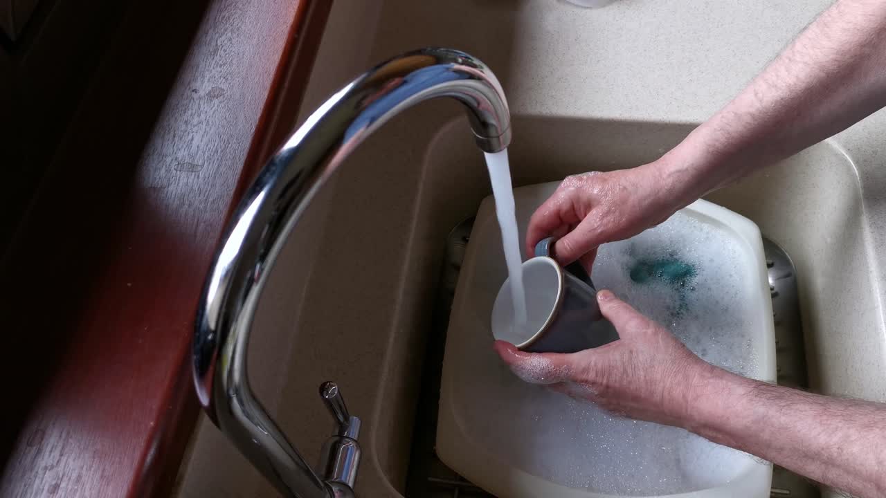 Washing mugs in the kitchen with plenty of soapy bubbles