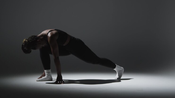 Ganzkörper-Studioaufnahme einer Frau in Sport-Fitnesskleidung beim Dehnen