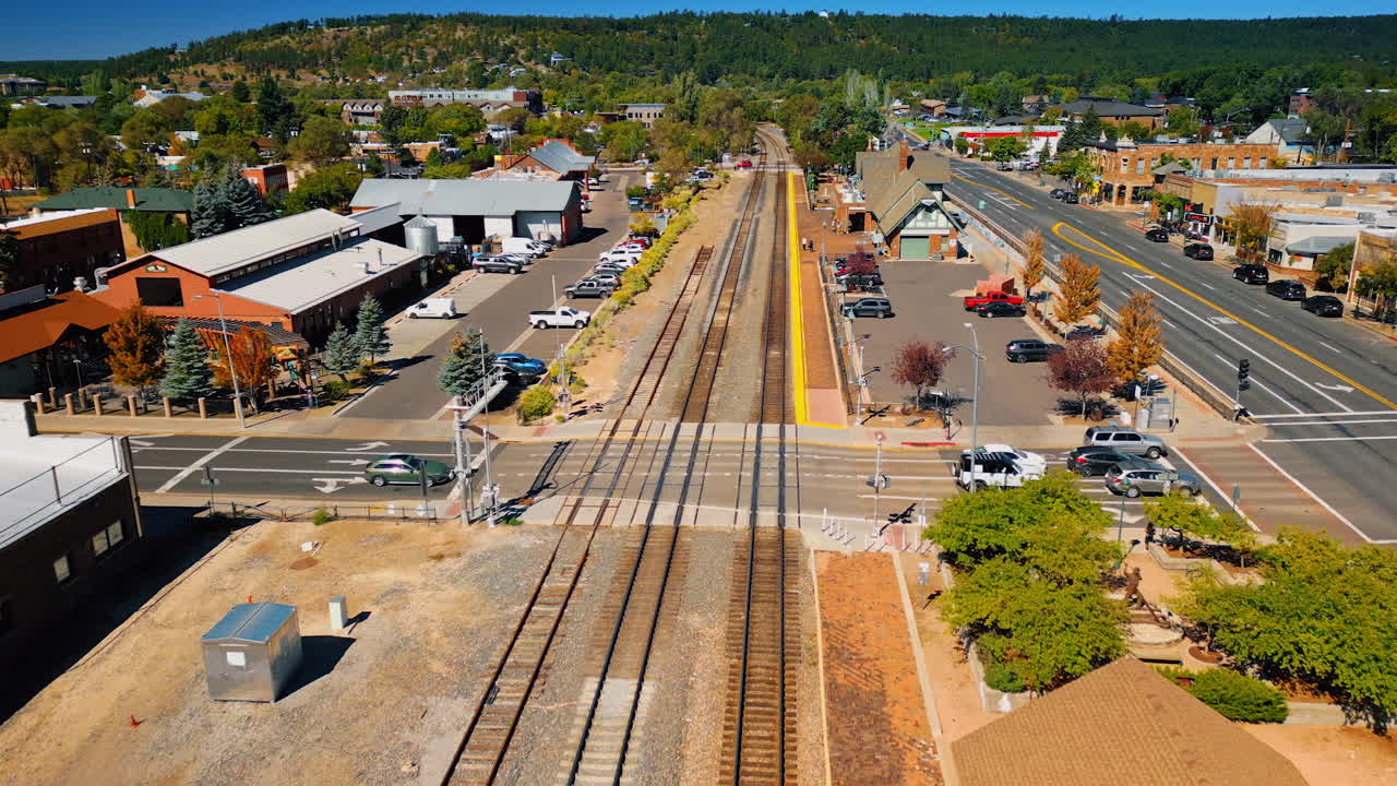Flagstaff, USA, 24 August 2025: Moving above the railways approaching a small station. Sunny green scenery of Flagstaff, Arizona, USA with verdant hills at backdrop