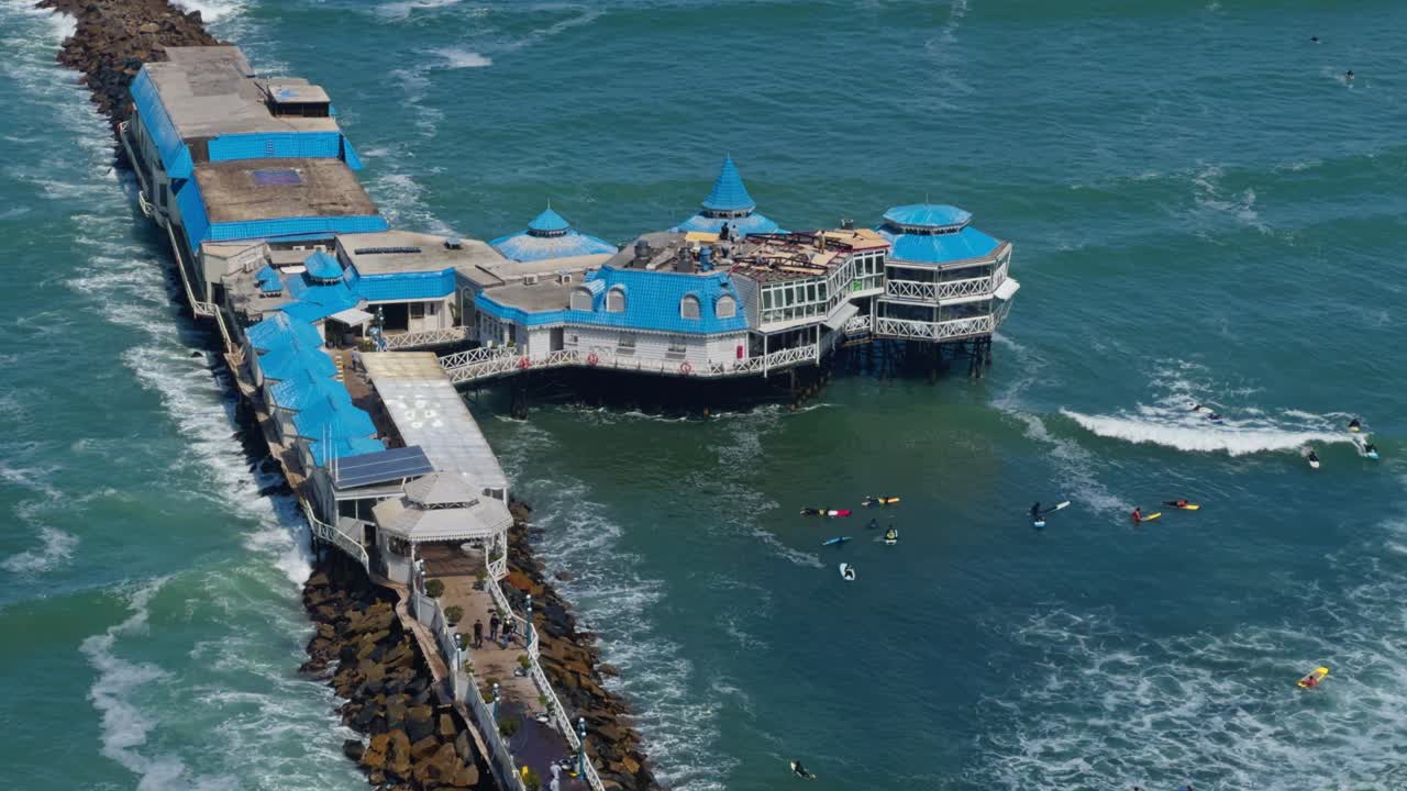 Establishing telephoto slow motion of La Rosa Nautica Lima Peru, ocean pier, gentle waves, deep water and structural columns