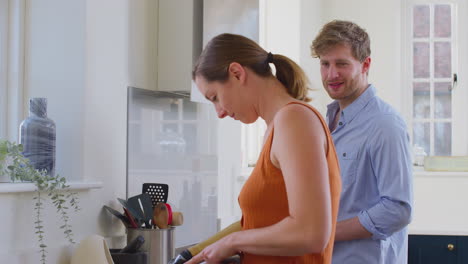 couple with woman with prosthetic arm in kitchen preparing meal together