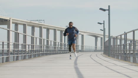 focused sportsman with artificial leg running along embankment in the morning