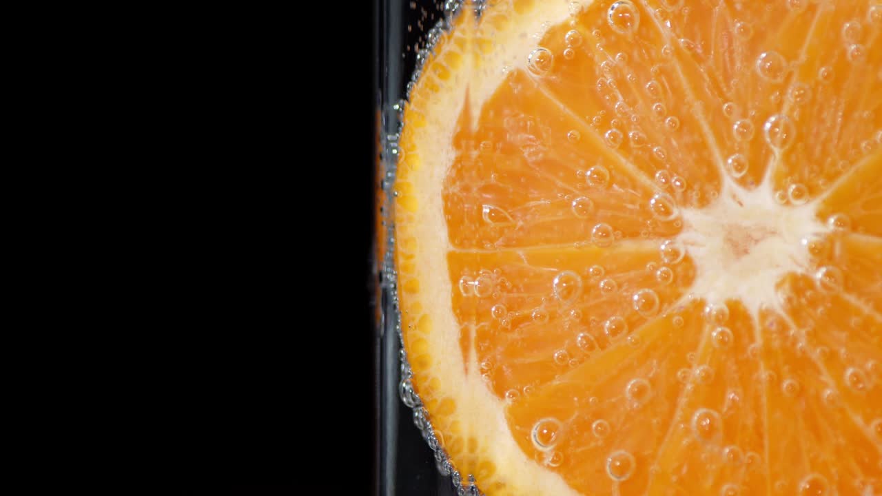 Uno spicchio di mandarino maturo sott'acqua con bolle d'aria