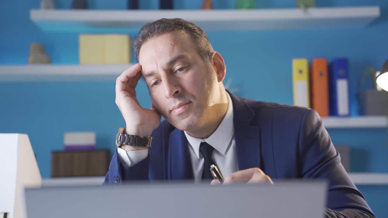 Close-up portrait of thoughtful businessman working with laptop in office.