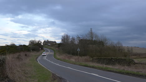 Coches-Circulando-Por-Una-Carretera-Rural-Británica-En-Un-Día-Nublado