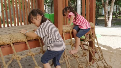 active little sisters having fun in the outdoor playground in the park. cute little girls climbing and sliding down on children playground. play is learning in childhood.