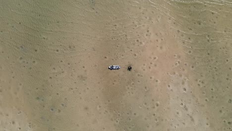 A-kayak-tied-to-a-tree-stump-floats-calmly-in-the-clear-waters-of-a-natural-sand-island