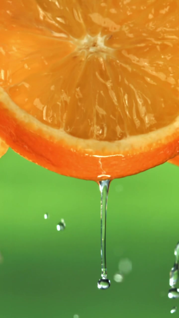 Gocce d'acqua che cadono da una succosa fetta d'arancia al rallentatore