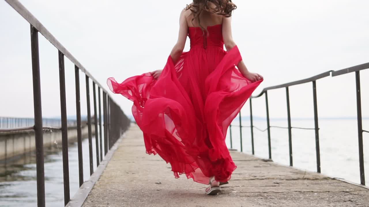 Woman in a Red Dress Running on a Pier