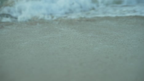 Low-angle-shot-of-surf-coming-towards-beach