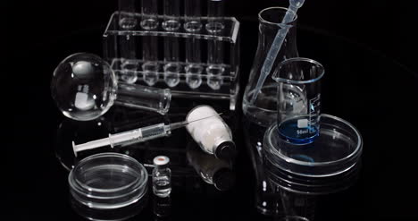 equipo de laboratorio: jeringas y tubos de ensayo de medicamentos y matraces girando sobre fondo negro 6