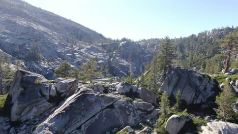 Un-Dron-Cienmático-De-Alta-Resolución-De-4k-Vuela-Más-Allá-De-Una-Línea-De-árboles-Para-Revelar-Un-Lago-Alpino-De-Aguas-Profundas-Y-Claras-Debajo-De-Una-Cordillera-Nevada-Cubierta-De-árboles,-Bosques-Y-Rocas-Durante-La-Puesta-De-Sol-De-Verano