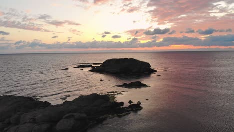toma aérea de un dron sobre un joven disfrutando del amanecer en las rocas en el mar cerca de lozenets, bulgaria