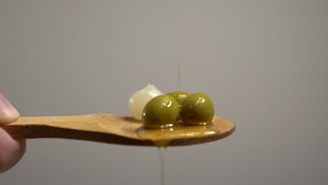 Cocktail-with-olives-on-wooden-spoon,-oil-falls-on-the-spoon