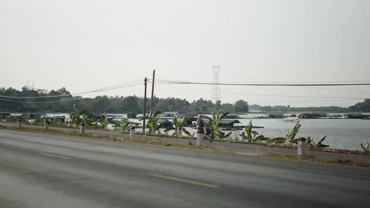 Roadside view of floating houses and a river
