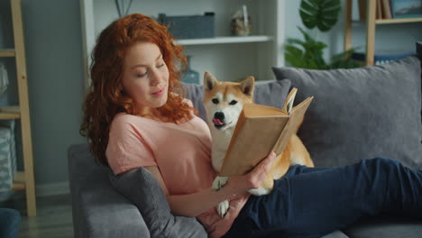 woman reading a book with her dog on the couch