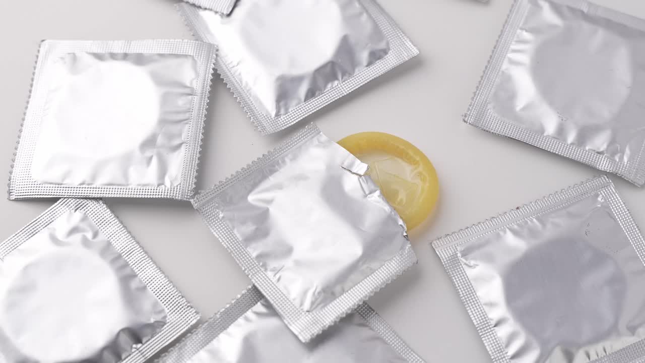 Mostrando embalagens de preservativos prateados em um fundo branco