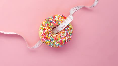 donut with measuring tape on pink background