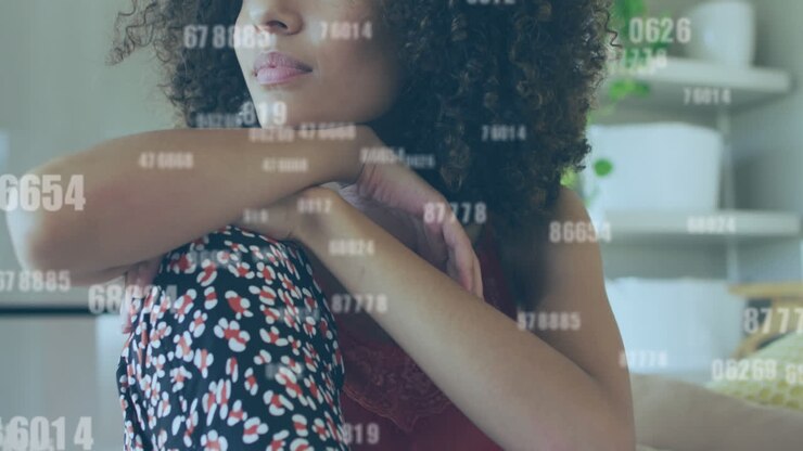 Animation of multiple changing numbers against thoughtul african american woman sitting at home