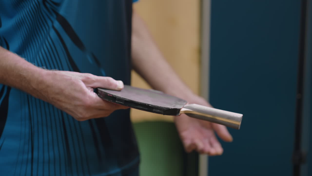 Close up partial view of athlete holding racket handle during tennis play, focus on grip and paddle technique, showing details of hand control, training practice, and intensity of indoor game