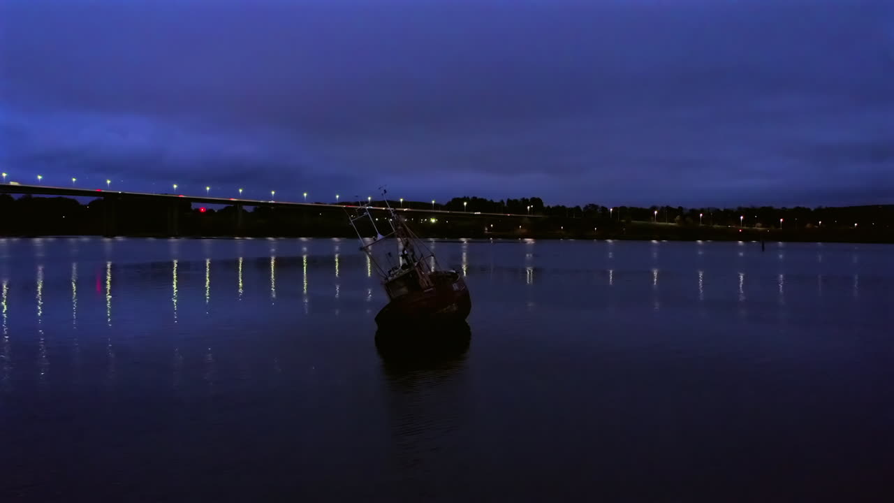 Aerial orbit around an old fishing boat with Foyle Bridge in the background, Londonderry