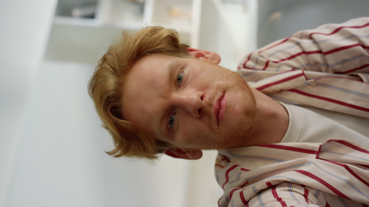 un tipo serio hablando por webcam con un amigo en primer plano. un hombre rojo molesto asintiendo