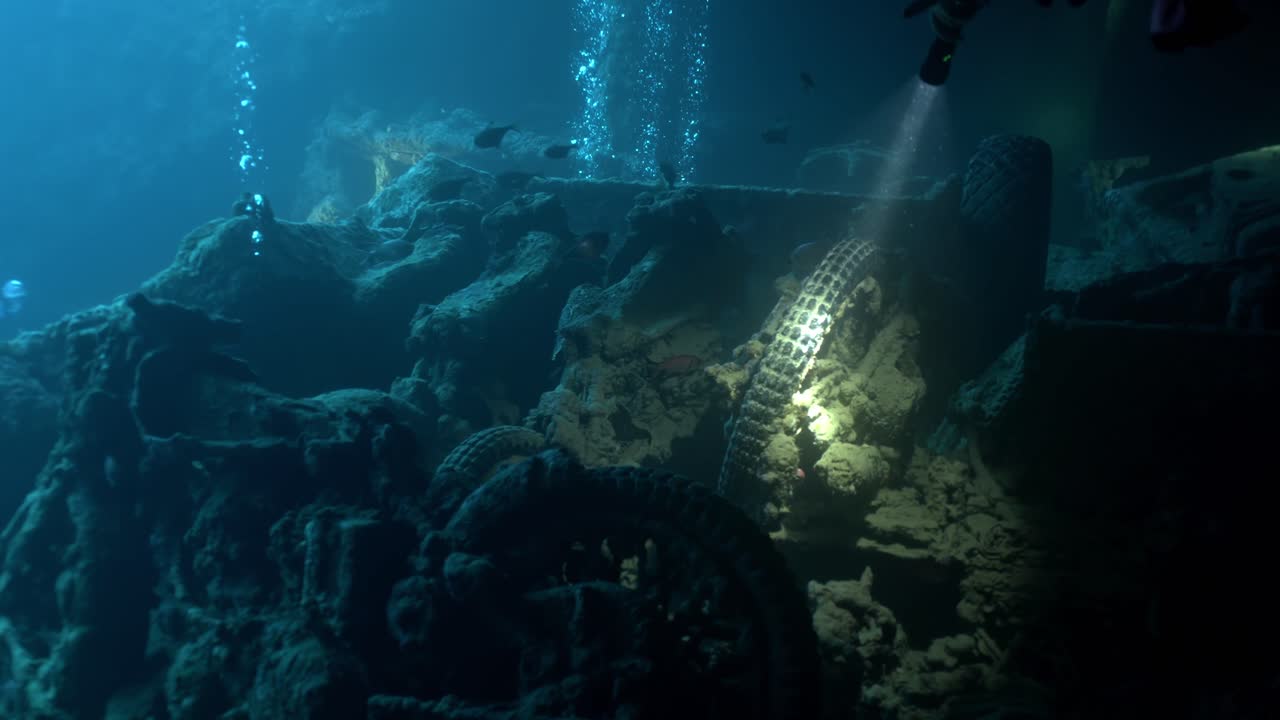 Ein Taucher nutzt eine Tauchlampe, um die Schatten von Hold No. 2 in der SS Thistlegorm zu durchdringen und die BSA M20 Motorräder im Heck eines Bedford-Trucks sichtbar zu machen
