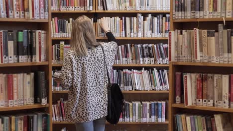 young girl walking between bookshelves in library, static shot with books all around