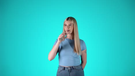 Cute-blonde-woman-tossing-cheers-with-glass-bottle-and-drinking-fresh-water