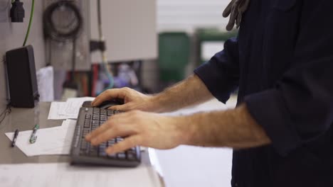 man at the workshop in uniform use computer for his job for fixing broken car