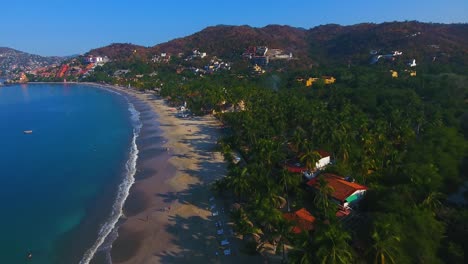 flying straight down a beach lined with palm trees and shops on the coast of a tropical paradise in the summer