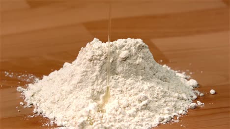 egg pouring onto flour on table