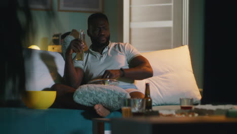 man watching tv and drinking beer at home