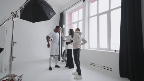 art director checking the photos on a monitor. professional crew team together in the studio. behind the scene of photo shooting professional football player and production set up in the big studio.