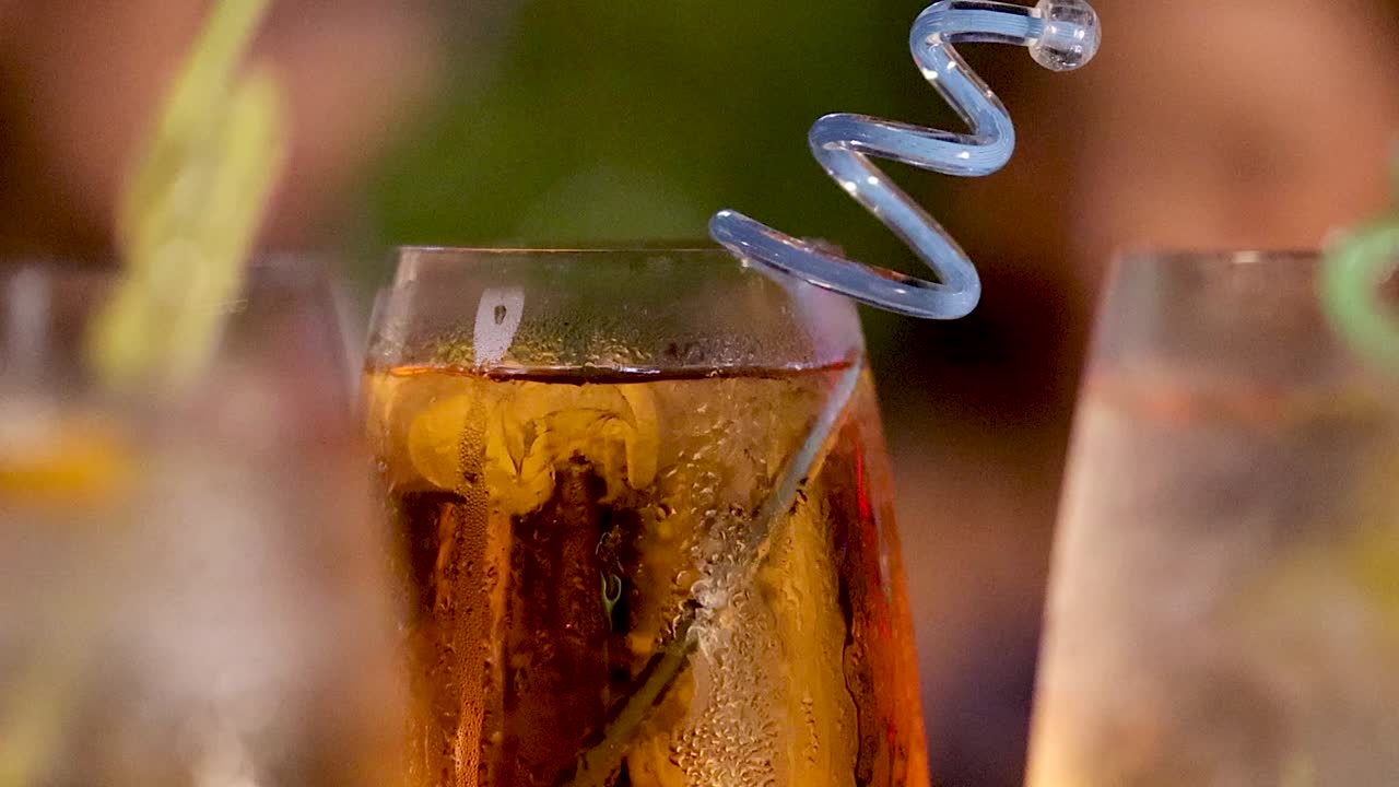 Primerísimo primer plano de un vibrante cóctel naranja con una pajita azul en espiral y condensación