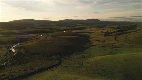 Ein-Drohnenschuss-über-Den-Hügeln-Von-Yorkshire-Dales-Mit-Flussrauschen-Zur-Goldenen-Stunde