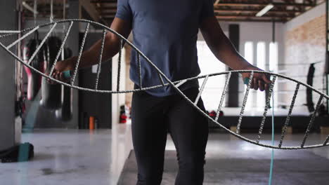 animation of dna strand over biracial man jumping rope at gym