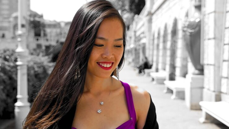 Donna in abito vivace che sorride allo Stadtpark di Vienna, effetto colore selettivo, giornata di sole.