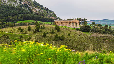 statischer blick auf den dorischen tempel von segesta, provinz trapani, sizilien, italien bei tag im zeitraffer in ländlicher landschaft über hügeligem gelände